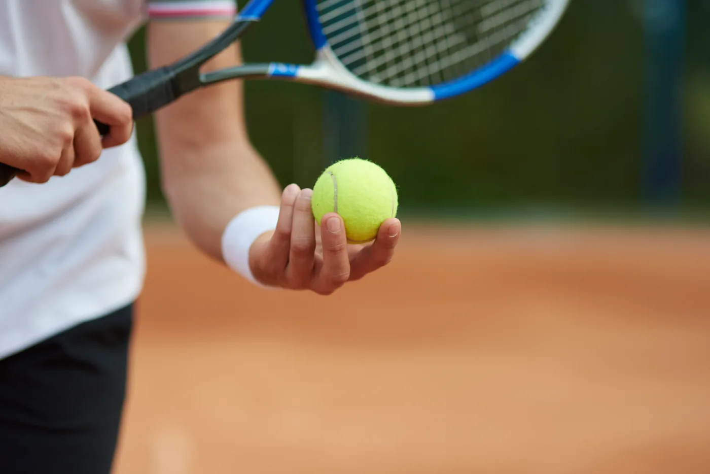 Tennis player holding a ball and racket on a court